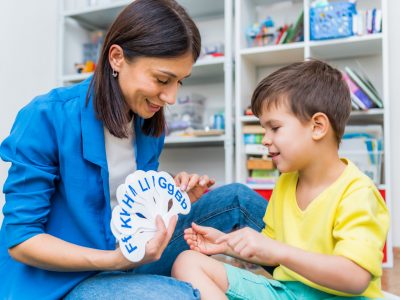 A cute child with a speech therapist is taught to pronounce the letters, words and sounds correctly.