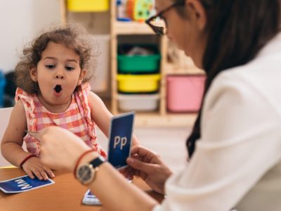 psychologist having speech support session with young girl in kindergarden